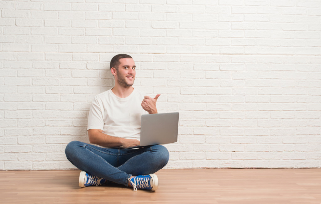 man doing a thumbs up while using his laptop sitting