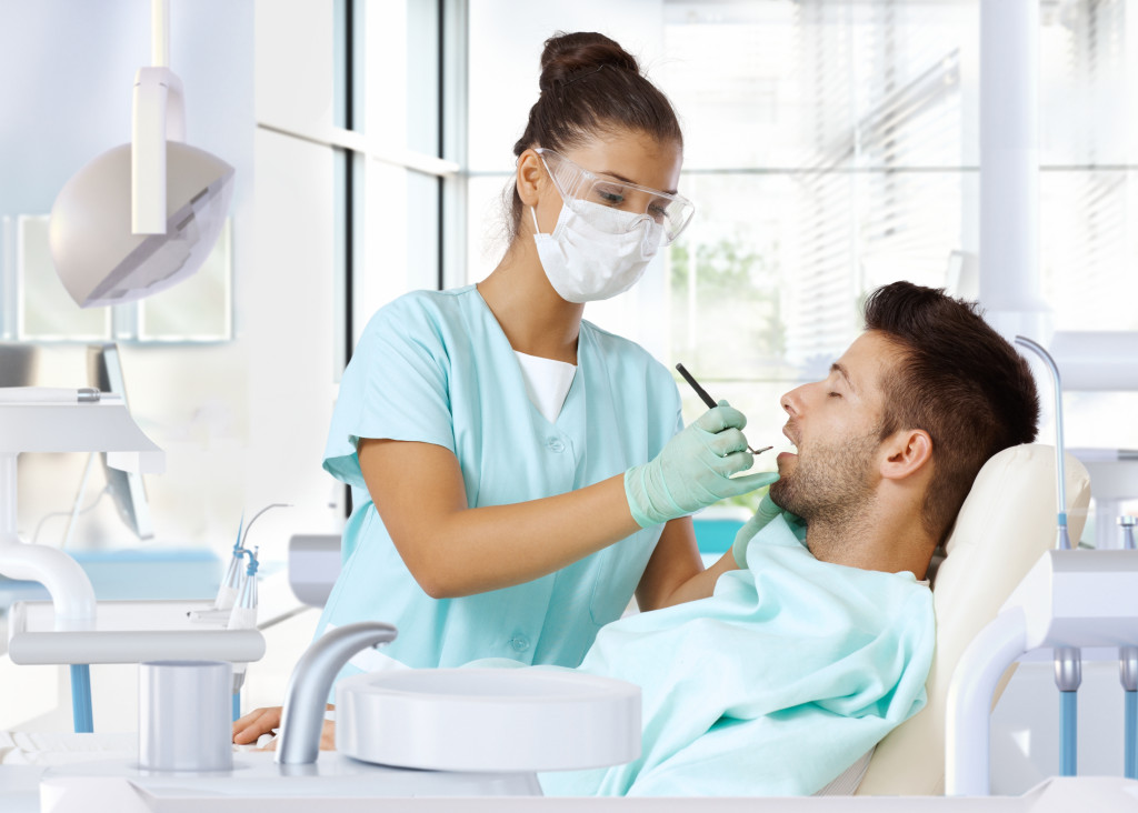 Young man on dental check-up, examined by female dentist.