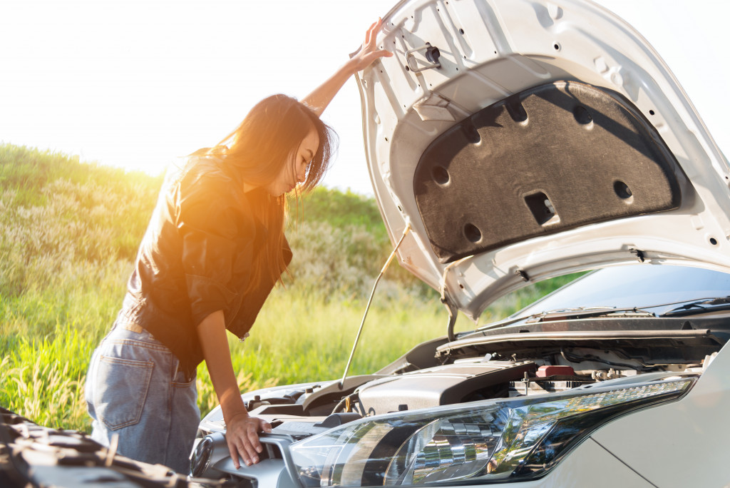 Woman looking at what is under the hood of a car