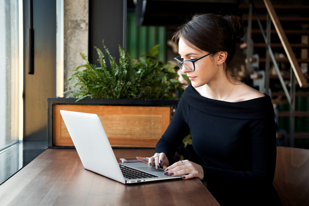 woman with glasses researching on her laptop