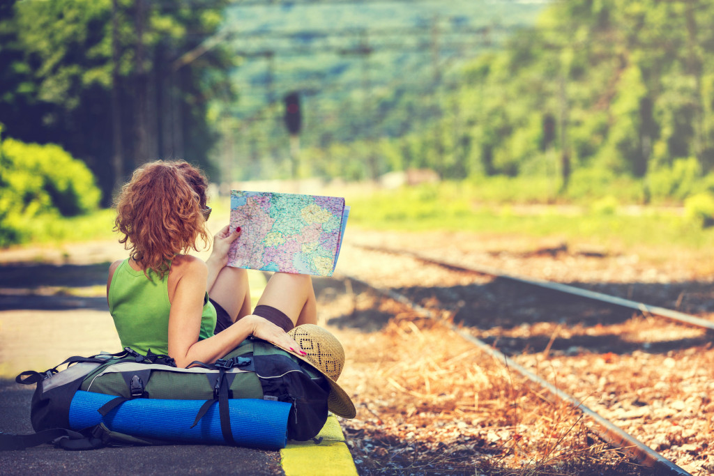 woman looking at a map sitting next to a train rail