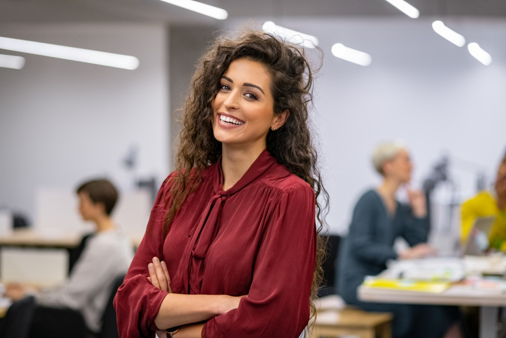 beautiful curly haired woman smiling while standing confidently in office