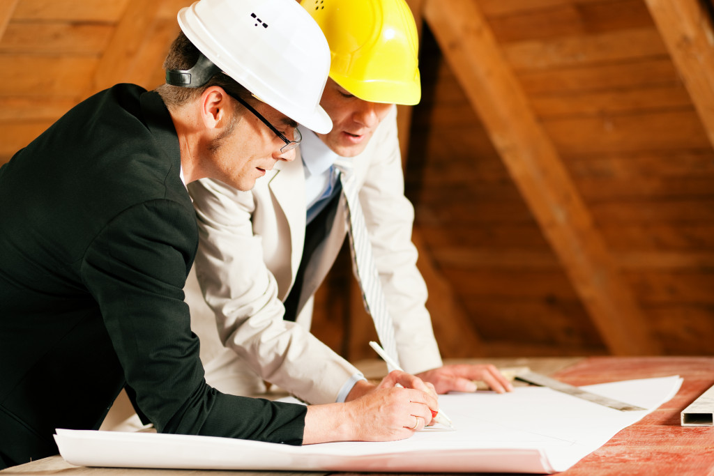 engineer and contractor discussing a building plan wearing hard hats
